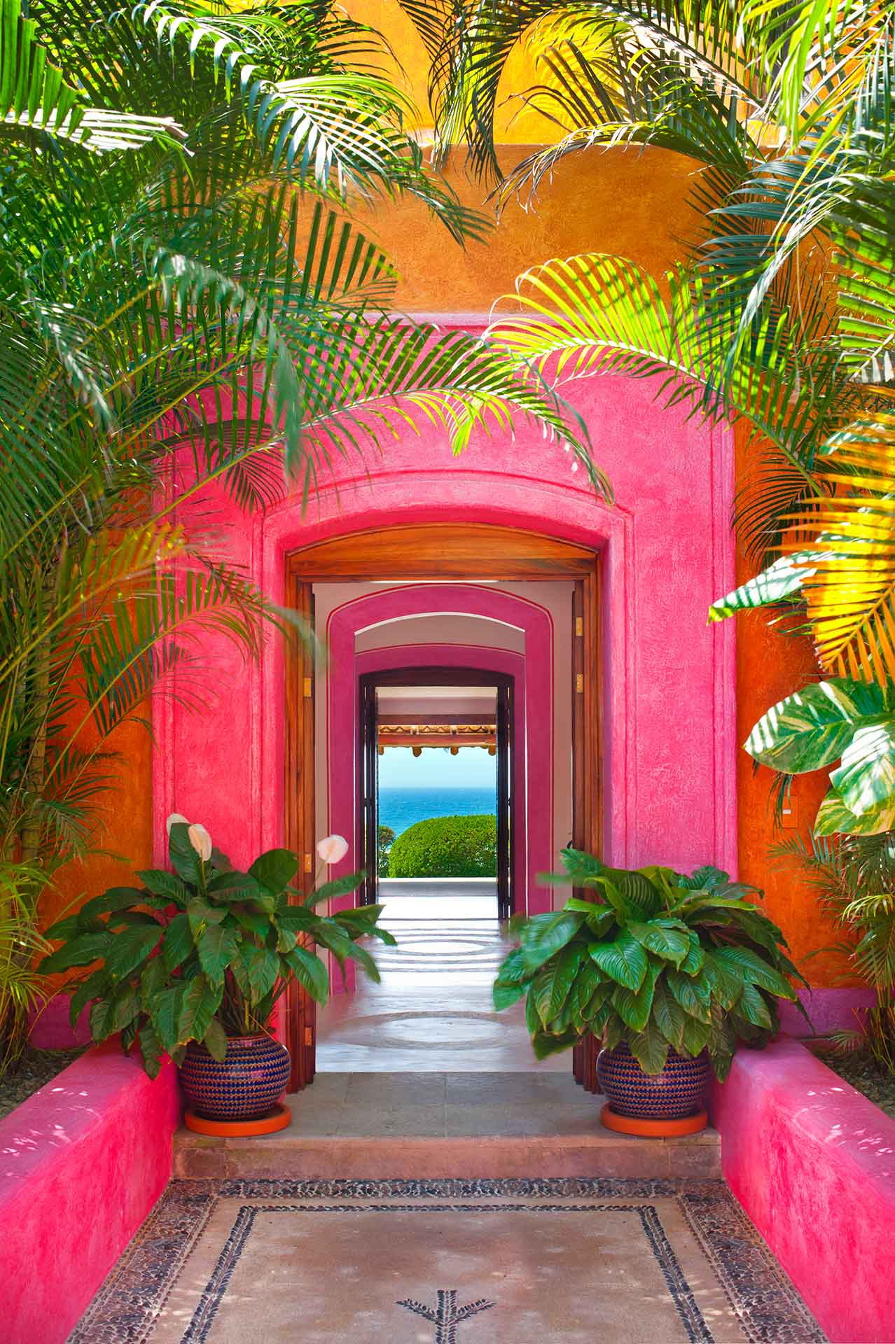 Entrada con las puertas abiertas con marcos color rosa que muestra la vista al mar en hotel las Alamandas.