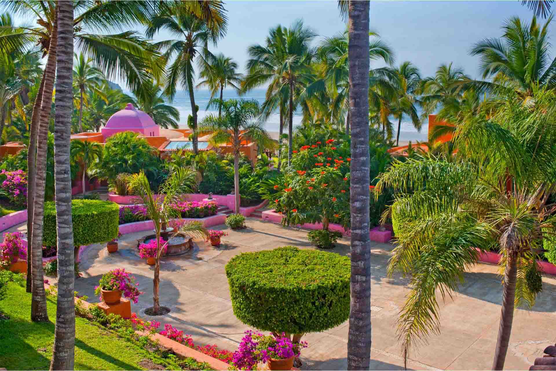 Jardín del hotel Las Alamandas con vista al mar al fondo.